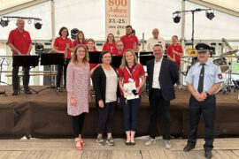 Im Festzelt erhielt Theresa Schäl und die Frankenthaler Feuerwehrkapelle (im Hintergrund) die Auszeichnung zum Ehrenamt des Monats von Landrat Udo Witschas (2.v.r.) im Beisein der Ehrenamtsbeauftragten Dunja Reichelt (l.) sowie der Bürgermeisterin der Gemeinde Frankenthal Janine Bansner (2.v.l). Vom Gemeindewehrleiter Kay Winkler (r.) erhielt Theresa Schäl außerdem die Verdienstmedaille des Landesfeuerwehrverbandes Sachsen e.V.